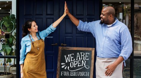 cheerful business owners standing with open blackboard