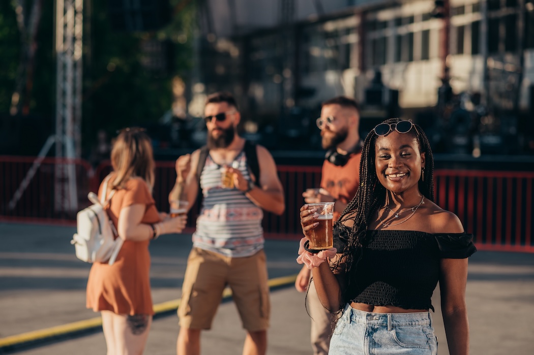 group of friends drinking beer and having fun at music festival